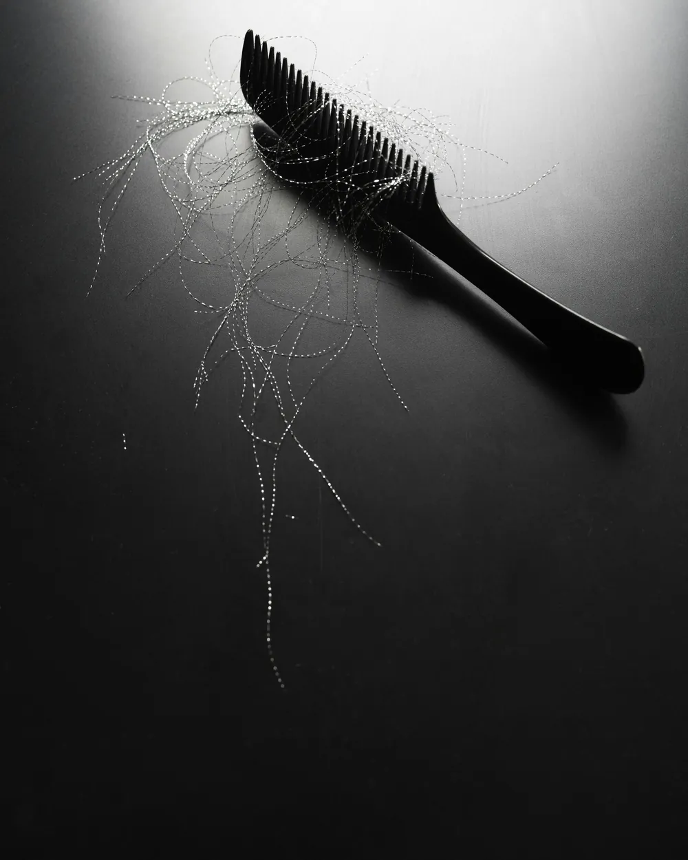 Comb with fallen hairs on a dark surface